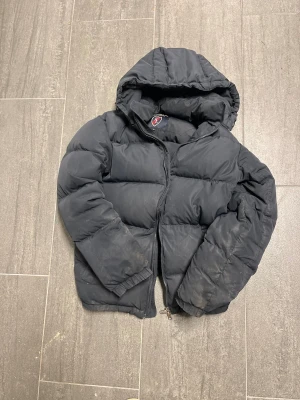 Svart puffer ridjacka från Kingsland XS - Svart pufferjacka ridjacka från Kingsland i storlek XS. Jackan har huva, dragkedja framtill och breda, quiltade sektioner. Perfekt för kalla dagar! Tvätt av jacka skes innan vi skickar den. Hör av er om ni har frågor angående pris eller något annat!