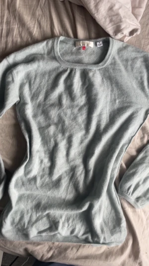Ljusgrå kashmirtröja från Uniqlo - Superskön ljusgrå kashmirtröja från Uniqlo i storlek S. Tröjan har rund hals, långa ärmar och ribbade muddar vid ärmslut och nederkant. Perfekt för Ljusgrå kashmirtröja från Uniqlo!!💕