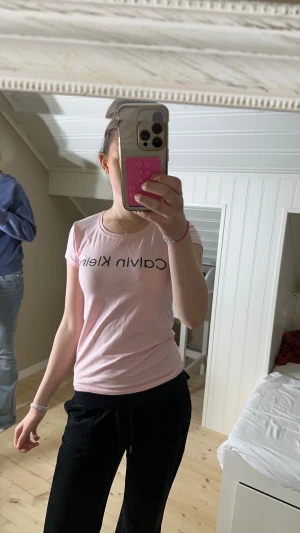 Ljusrosa Calvin Klein t-shirt i bomull - Säljer en ljusrosa t-shirt från Calvin Klein i storlek M men sitter som en S. T-shirten har korta ärmar, rund hals och svart logotyptryck framtill. Materialet är mjuk bomull och passformen är normal. Perfekt för dig som gillar stilrena och klassiska plagg med en modern touch.