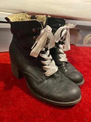 Svarta boots med klack och vita snören - svarta boots med klack och vita satinsnören. jättemysigt foder på insidan. yttermaterialet är i skinn och har dragkedja på sidan. perfekta för höst och vinter (: