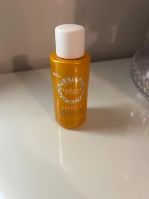 Lumene Valo Glow Beauty Lotion - Lumene Valo Glow Luminizing Beauty Lotion med C-vitamin i en snygg orange plastflaska med vitt lock. Perfekt för att ge huden extra lyster och fräschör. Innehåller 50 ml och passar alla hudtyper.