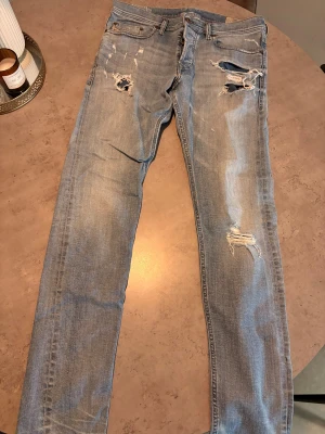 Ljusblå slitna jeans från Diesel, stl 31 - Säljer ett par ljusblå jeans från Diesel med snygga slitningar och hål på låren och knäna. Jeansen har klassisk femficksdesign, raka bakfickor.