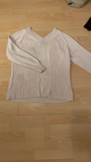 Beige stickad tröja från Oui Moments - Snygg beige/rosa stickad tröja från Oui Moments med v-ringad hals och ribbade detaljer längs kroppen och ärmsluten. Långärmad och mjuk, perfekt för lager på lager under kyliga dagar. Enkel att matcha med jeans eller kjol för en chill look. Står ingen exakt storlek men skulle nog säga storlek S