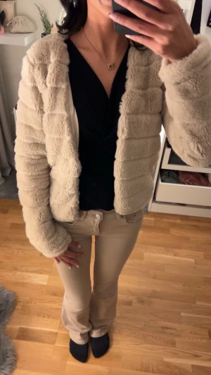 Beige pälsjacka från Gina Tricot - Säljer en fluffig och supermjuk beige pälsjacka från Gina Tricot. Jackan har ett croppat snitt, långärmade ärmar och horisontella sömmar som ger en cool struktur. Perfekt för dig som vill ha en cozy vibe och samtidigt se stylish ut.