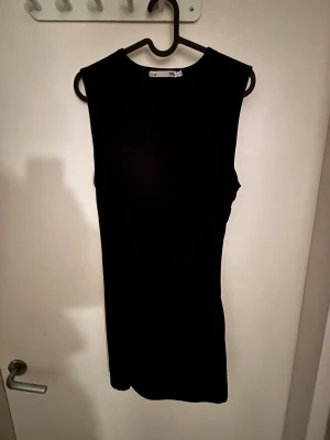 Svart kortare klänning från 157 - Svart långklänning från 157 med ärmlös design och rund halsringning. Klänningen har snygga rynkade detaljer längs sidan som ger en cool och modern siluett. Materialet känns mjukt och följsamt, perfekt för dig som gillar minimalistisk stil. Aldrig använd, endast testad. Hör av dig via e-mejl eller mobilnummer då jag inte kan ta emot Swish på detta nummer. E-mejl emli.com@icloud.com mobil-0728875624 mvh Emilia/marina😊