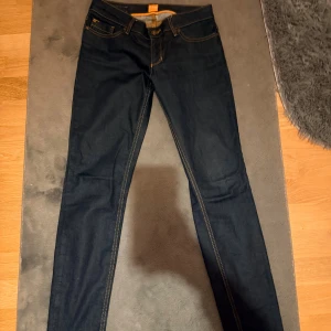 Mörkblå skinny jeans  - Snygga mörkblå jeans från Boss med kontrasterande orange sömmar och klassisk femficksdesign. Modellen är skinny med high waist. Inte använt! 
