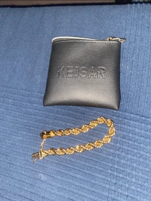 Cordell länk från Kejsar - Säljer ett snyggt cordell guldarmband  från Kejsar med tvinnad kedja och robust lås. Armbandet har en glansig finish och kommer med en svart förvaringspåse i skinnimitation med Kejsar-logga. Perfekt accessoar för att lyfta din stil. Priset kan diskuteras.