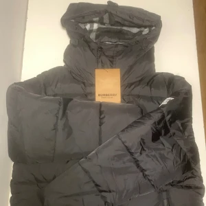 Burberry jacka  - Svart pufferjacka från Burberry med avtagbara ärmar så du kan bära den som väst. Skriv gärna om du vill diskutera om priset!