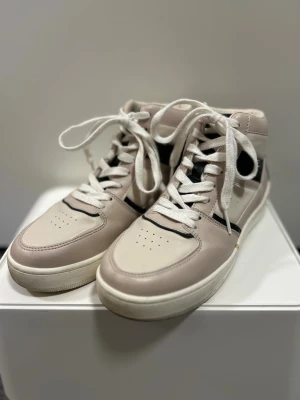Beige och vita high-top sneakers - Snygga high-top sneakers i beige och vitt med svarta detaljer. Skorna har rund tå, platt sula och klassisk snörning. Använd några få antal gånger! 💖👟