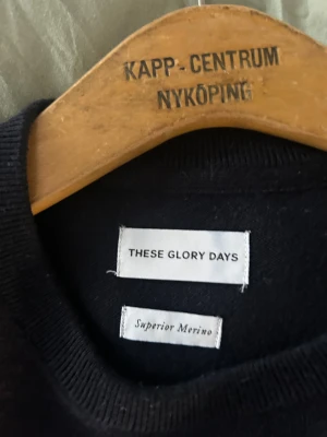 Mörkblå merinotröja These Glory Days - Snygg mörkblå stickad tröja från These Glory Days i mjuk superior merinoull. Klassisk rund hals och långärmad modell med ribbade muddar. Perfekt för dig som gillar stilrena och bekväma plagg med premiumkänsla. Tveka inte på att höra av dig kring eventuella frågor runt pris, storlek eller annat!