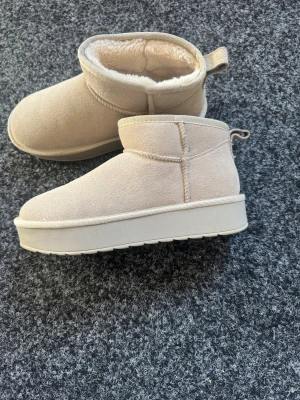Uggs med mocka och platå - Uggs med mocka och platå med ull i från din sko. Använda 1-2 ggr då dom är för stora för mig annars jätte bekväma och varma. Nypris 749 