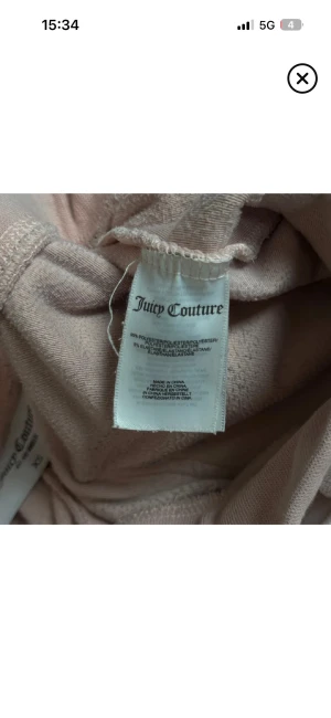 Rosa velourbyxor Juicy Couture XS - Mysiga ljusrosa mjukisbyxor från Juicy Couture i velour med snörning i midjan och stora fickor fram och bak. Byxorna har en relaxed passform och är perfekta för en chill och trendig look. Materialet är 95% polyester och 5% elastan.