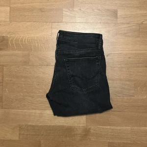 Jack & Jones jeans  - Svarta jeansbyxor från Jack & Jones  i modellen slim Glenn. Klassisk femficksdesign med snygga detaljer och smal passform. Jeansen har en mörk tvätt och raka ben, perfekta för dig som gillar en stilren look. Storlek 30/32.