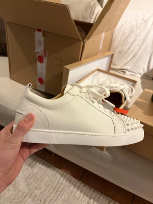 Christian Louboutin vita sneakers med nitar - Tjena säljer ett par Loubs som är vita med nitar ifrån miinto nypris ligger på 12-13 tusen dom var lite för stora dom passar runt 43,5-44 dom är storlek 44,5 dom är helt nya och har kvitto om det behövs får med box och dustbags.