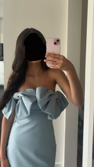 Ljusblå klänning med rosetter - Superfin ljusblå kortklänning från Zara med stora rosetter upptill och axelbandslös design. Klänningen har en slim passform och är gjord i ett mjukt polyestermaterial som sitter snyggt. Perfekt för dig som vill sticka ut med en unik look.