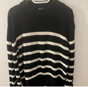 Randig svartvit stickad tröja Gina Tricot - Säljer en svart stickad tröja från Gina Tricot med vita horisontella ränder. Tröjan har rund halsringning, långa ärmar och en relaxed fit. Perfekt för dig som gillar en enkel men snygg look med lite edge.