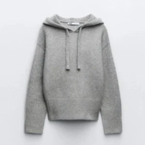 Grå stickad hoodie från Zara - Mysig grå hoodie från Zara med huva och snörning. Tröjan är stickad i mjukt material och har breda ribbade muddar vid ärmslut och nederkant. Perfekt för chill dagar och snygg att styla.