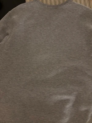 Grå sweatshirt från Polo Ralph Lauren XL - En stilren grå sweatshirt från Polo Ralph Lauren i storlek XL. Tröjan har rund halsringning, långa ärmar och klassisk broderad logga på bröstet. Perfekt basic i garderoben och skön att bära tack vare mjukt bomullsmaterial.