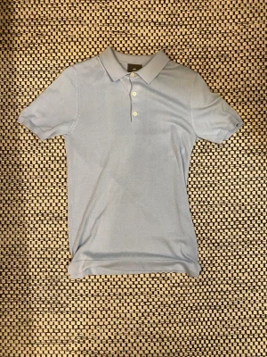 Ljusblå slim fit piké från H&M - Snygg ljusblå piké från H&M i slim fit.                               XS