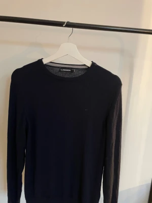 Stickad tröja J.Lindeberg - Snygg mörkblå stickad tröja från J.Lindeberg med diskret logga broderad på bröstet. Tröjan har rund hals och långa ärmar, perfekt för dig som gillar stilrena och klassiska plagg. Materialet är mjukt och skönt mot huden. Tröjan är i storlek s men sitter som xs. Nypriset ligger på 1300kr.