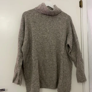 Beige polotröja från Bik Bok i ullmix - Mysig beige polotröja från Bik Bok i ullblandning. Tröjan har en loose passform, ribbad struktur och långa ärmar. Perfekt för kyliga dagar och enkel att styla med jeans eller leggings. Polokragen ger extra värme och en chill vibe.