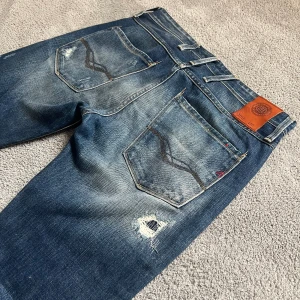 Replay Anbass Jeans - Säljer dessa galet feta Replay Anbass Jeansen som har en riktigt fet tvätt med sköna slitningar. Storleken är 31/34 men sitter mer som 31/32. De har absolut inte defekter, som nya! Hör av er🫡