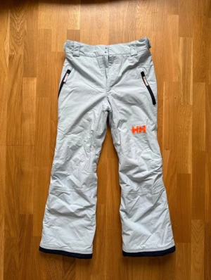 Ljusblåa Helly Hansen skidbyxor - Jätte fina Helly Hansen skidbyxor som har blivit för små för mig! Dem är fortfarande toppen skick eftersom de bara användes under två skidsäsonger! Normal i storleken. Dem har även RECCO spårning! Nypris 1000 kr