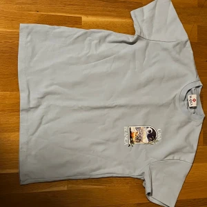 Ljusblå Casa Blanca t-shirt med tryck - Snygg ljusblå t-shirt från Casa Blanca med stort färgglatt tryck på ryggen och mindre tryck på bröstet. T-shirten har klassisk passform, rund hals och är tillverkad i mjuk bomull. Perfekt för dig som vill sticka ut med cool grafik och streetwear-vibe.