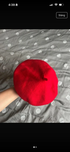 Röd basker i ull med snörning - Säljer en klassisk röd basker med rund form och snörning på insidan för justerbar passform. Tillverkad i mjuk ull som håller dig varm och ger en snygg vibe. Perfekt för dig som vill sticka ut med en färgklick på huvudet.