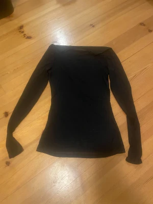 Svart  genomskinlig topp - Säljer en svart mesh topp med lång ärm och tight passform. Toppen är helt genomskinlig och har en enkel, stilren design med rund hals. Perfekt för att styla lager på lager eller som statement-plagg. Materialet är lätt och stretchigt syntet.