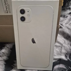 iPhone 11 - Snygg vit iPhone 11 i originalförpackning. Mobilen har dubbla kameror, stor skärm och ser ut att vara i mycket gott skick utan synliga repor eller skador. Perfekt för dig som vill ha en pålitlig och modern smartphone från Apple.