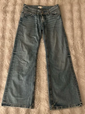Blå wide jeans från Gina Tricot - Säljer ett par ljusblå jeans från Gina Tricot i storlek 152. Modellen har breda ben och klassisk femficksdesign med snygga detaljer på bakfickorna. Jeansen har låg midja och är tillverkade i jeansmaterial med kontrastsömmar.