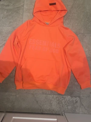 Essentials Fear Of God Hoodie Coral/Orange S - Fick denna i julklapp av mina föräldrar men i fel storlek!🥹Jättefin och unik färg🤗Nypris:2990 (Sitter även lite oversize) pris kan säkert diskuteras också!