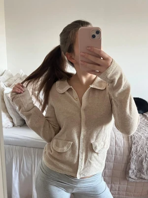 Beige Kashmir och ull kofta - Superfin beige kofta med dekorativa detaljer. Koftan har stickade detaljer längs kanterna och guldknappar. Den är från märket byTimo och inköpt för lite mer än 3000 kr, tröjan är helt oanvänd. Super mjuk och skön!💕