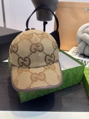 Keps  - Bilderna visar en beige och brun keps med GG-mönster, inte en väst. Ingen information om väst kan ges.