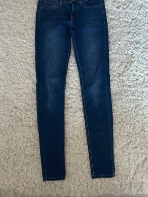 Levi's 710 Super Skinny jeans blå - Säljer ett par Levi's 710 Super Skinny jeans i mörkblå tvätt. Modellen har smal passform hela vägen ner, klassiska fem fickor och Levi's patch bak. Jeansen är tillverkade i stretchig denim med snygga kontrastsömmar.