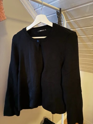 Svart kofta  - En enkel svart kofta från Gina Tricot med rund hals och en knapp framtill. Koftan har långa ärmar och är stickad i mjukt material, perfekt att slänga över en t-shirt eller linne. Aldrig använd bara testad. Är storlek Xs men passar även S. Skriv för bilder/frågor eller intresse!🩷