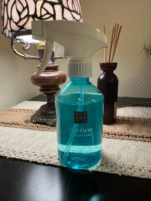 Rituals Parfum d'Interieur spray - En flaska med Rituals Parfum d'Interieur, en blå doftspray i plastflaska med vit spraymunstycke. Perfekt för att fräscha upp hemmet med en lyxig doft. Flaskan har en modern design och rymmer 500 ml.