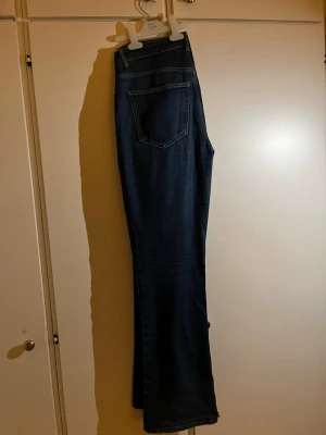 Bootcut jeans från Perfect Jeans, blå - Snygga mörkblå bootcut jeans från Perfect Jeans i storlek 40. Klassisk femficksmodell med hög midja och raka ben som breddas nedtill. Jeansen är tillverkade i ett slitstarkt bomullsmaterial med lite stretch för extra komfort. Perfekt för dig som gillar retrovibbar och vill ha ett par jeans med schysst passform. Lite urtvättade men annars fin skick!! 