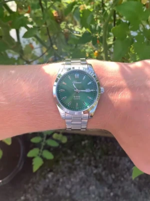 Grön quartzklocka från Doventi  - Snygg klocka med grön urtavla och silverfärgad länk i metall. Urtavlan har minimalistiska index och datumvisning vid kl 3. Quartz-urverk och stilren design som passar till många outfits. Perfekt för dig som gillar att sticka ut med accessoarer. Skickas med box, går att ändra storlek 