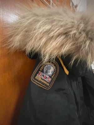 Svart Parajumpers parkajacka XXS - Säljer en svart Parajumpers Anchorage parkajacka i storlek XXS. Jackan har stor fluffig päls på huvan, flera fickor, patch på ärmen och coola gula detaljer. Perfekt för kalla dagar och har en snygg, lite längre passform.