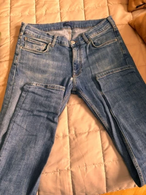 Blå jeans från GANT, storlek 158/164 - Snygga blå jeans från GANT med klassisk femficksdesign och ljus tvätt. Jeansen har normal passform, raka ben och är tillverkade i slitstarkt bomullsmaterial. Perfekt för dig som gillar en enkel och tidlös stil. Märkespatch i läder baktill.