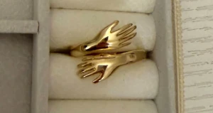 Guldfärgad ring med handmotiv - Unik guldfärgad ring med två detaljerade händer som möts framtill. Ringen har en modern och cool design som sticker ut och passar perfekt för dig som gillar statement-smycken.