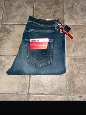 Replay Hyperflex jeans - Snygga Replay Hyperflex Super Slim jeans i klassisk blå tvätt med coola slitningar och kontrastsömmar. Modellen har fem fickor och stretchigt material som ger grym passform. Midja 36 cm / längd 109. Jag tar ej bilder när jag har på jeansen.