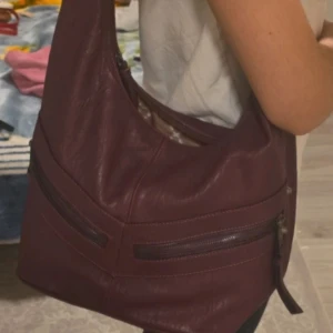 Vinröd axelväska Jessica Simpson vintage - Accepterar alla bud! Då artikeln tas bort snart!!! Snygg vinröd axelväska från Jessica Simpson. Perfekt för någon som går i skolan då min apple ipad går in på väskan utan problem. Har slitits. Har många fickor och ganska stor. Priset kan diskuteras 