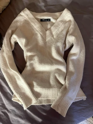 Vit stickad v-ringad tröja FB Sister - Mysig beige stickad tröja från FB Sister i storlek XS. Tröjan har en djup v-ringning med bred ribbad kant och långa ärmar. Materialet är mjukt och ribbstickat, perfekt för kyliga dagar. Passformen är normal och modellen är enkel men snygg. Jag har sytt in den i midjan för en mer snatched look. Pris går att diskutera 💕