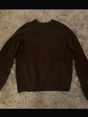 Mörkbrun stickad tröja - Säljer en enkel och stilren mörkbrun stickad tröja med rund hals och långa ärmar. Perfekt för kyliga dagar och passar till både jeans och kjol. Material lambswool