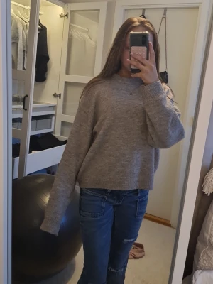 Beige stickad tröja från H&M - Mysig beige stickad tröja från H&M med rund halsringning och långa ärmar. Tröjan har en loose passform och ribbade muddar vid ärmslut och nederkant. 