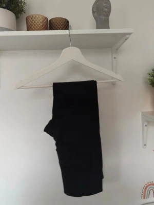 Svarta leggings i mjukt material oanvänt - Säljer ett par svarta leggings med tight passform. De är gjorda i ett mjukt och stretchigt material som sitter skönt mot kroppen. Perfekta att matcha med en oversized hoodie eller t-shirt. Passar dig som gillar enkel och stilren look.