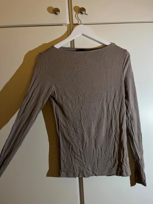 Beige långärmad topp i bomull - En enkel och stilren beige långärmad topp från lager 157. Modellen är rak med rund hals och tillverkad i mjuk bomull. Perfekt att matcha med jeans eller kjol för en clean look. Passar dig som gillar basic och neutrala färger.